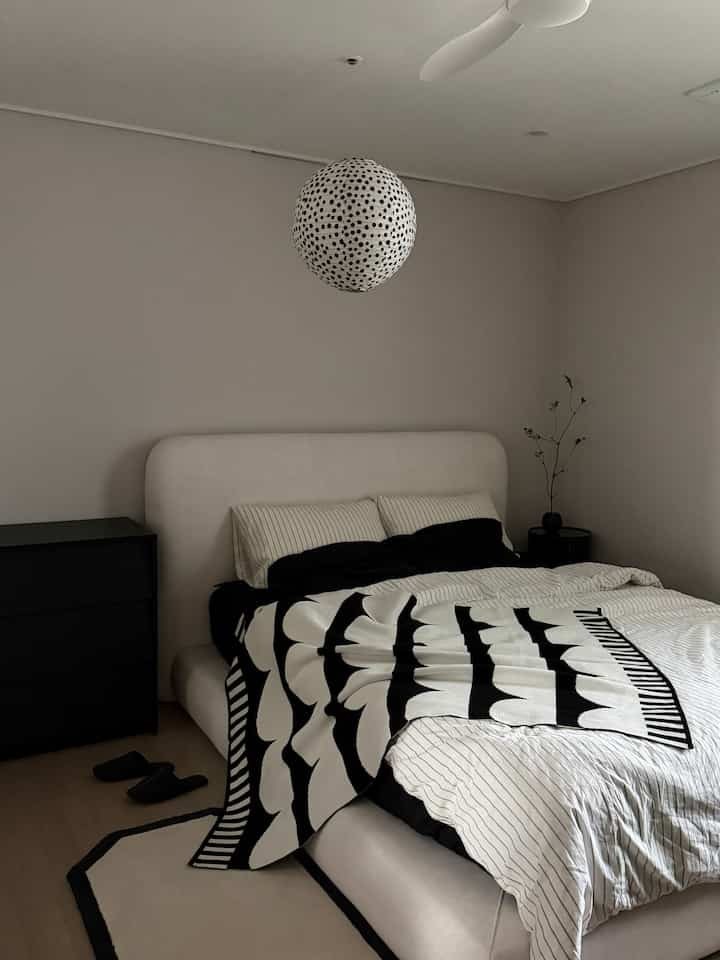 白と黒のモダンな寝室、中央にベッドとブランケットが配置された落ち着いた空間