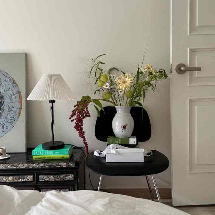 白と黒の寝室、中央に花瓶とフラワーアレンジメントが配置された自然でモダンなインテリア