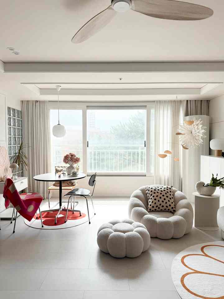 ホワイトとベージュのトーンのリビングルーム、円形のダイニングテーブルと曲線的なアームチェアが配置されたシンプルモダンな空間