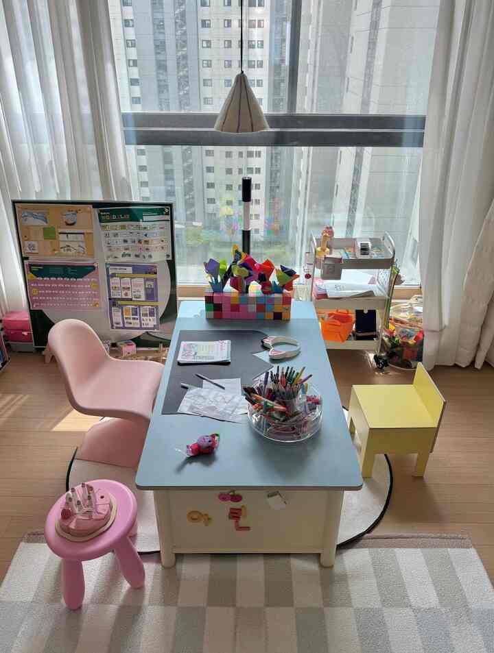自然光が差し込む窓際の子供部屋、子供用の机と椅子、整頓されたトロリーが配置された温かみのある印象的な空間