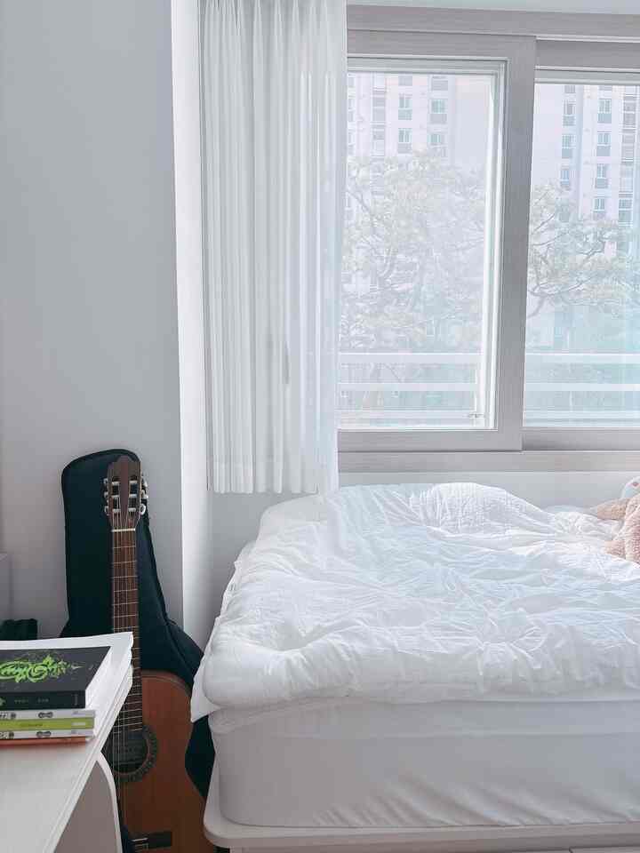 明るいホワイトトーンの子供部屋の寝室、大きなベッドと白いカーテンが配置された、清潔で居心地の良い空間