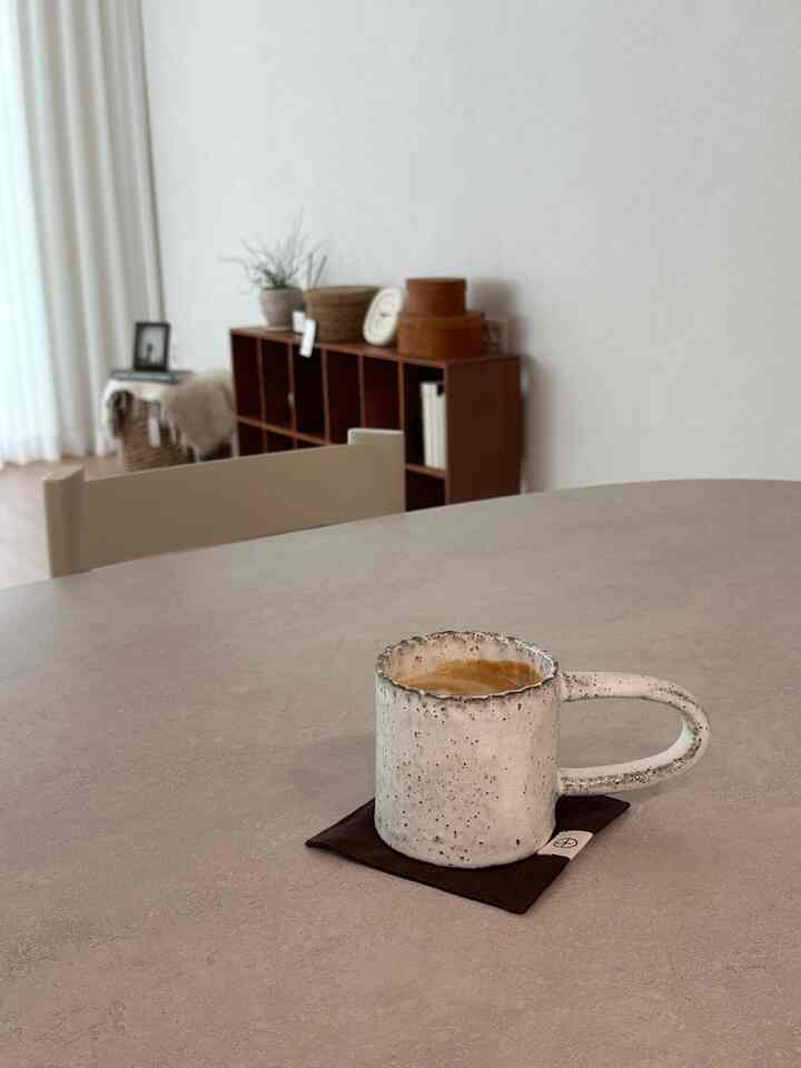 ベージュとウッドトーンが調和したナチュラルモダンなダイニングルーム、手作りの陶器のマグカップがテーブルに置かれた雰囲気のあるインテリア