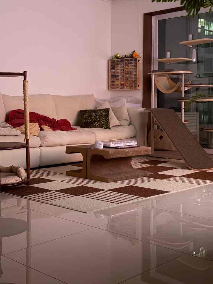 ナチュラルカラーのリビング、クリーム色のソファとチェック柄のラグ、キャットタワーが配置された印象的な空間