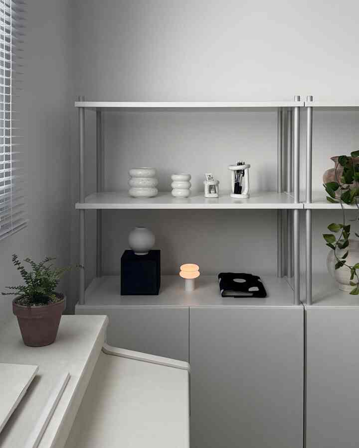 白とグレーのトーンでシンプルな書斎空間、セラミックオブジェと植物が配置された整ったインテリア