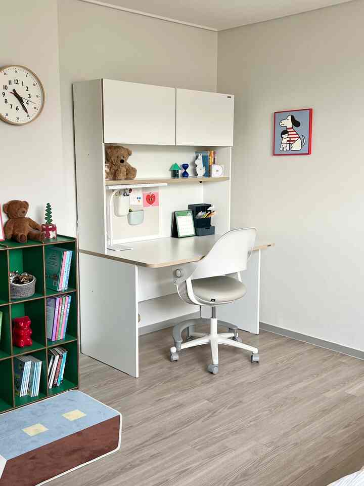 白と緑の色調の子供部屋、子供用デスクと椅子が配置された清潔で居心地の良い学習空間