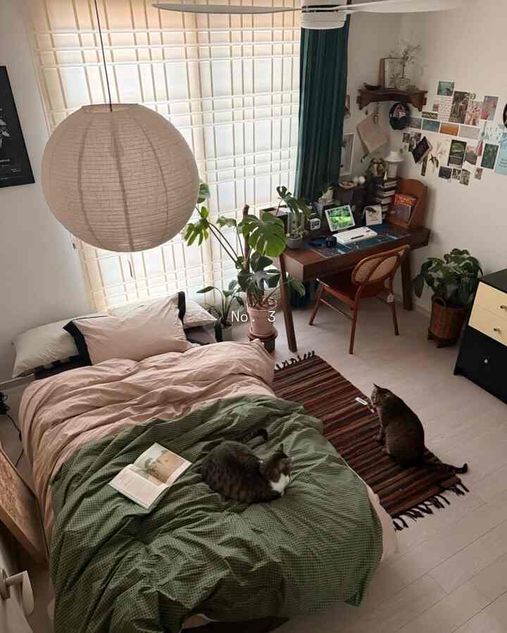 ナチュラルな色調と木製家具が融合した4.5畳のコンパクトな寝室、ベッドに2匹の猫とデスクが配置された温かみのあるインテリア