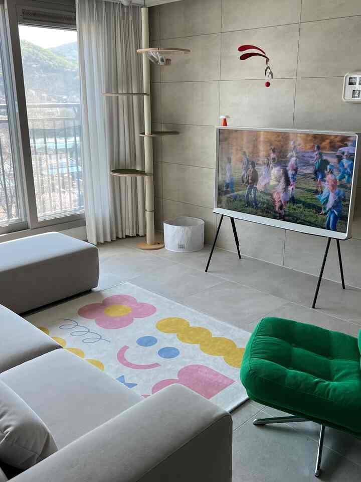 明るい白を基調としたリビング、キャットタワーと緑のアームチェアが配置されたシンプルでモダンな空間