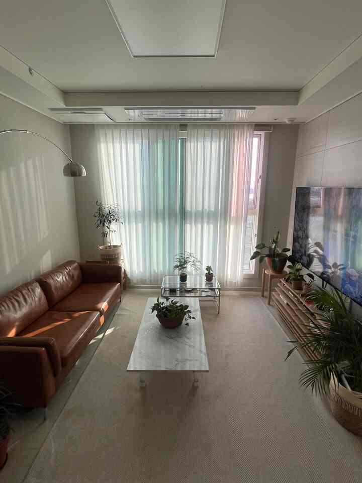 White and brown toned living room featuring a leather sofa and floor lamp in a bright, natural atmosphere