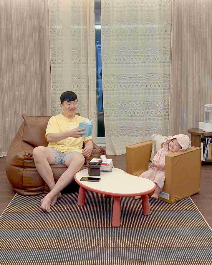 ベージュとブラウンの色調のリビング、ビーンバッグソファと子供用ソファが配置された家族中心の快適な空間