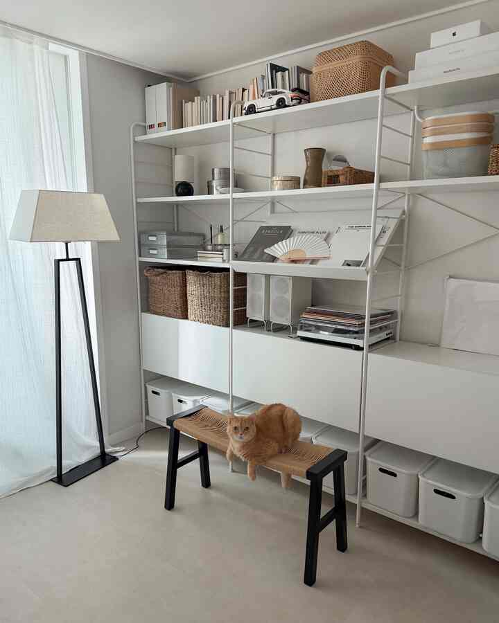 白い壁と棚があるモダンなリビング、ナチュラルトーンの黒いベンチに猫が座っている雰囲気のあるインテリア