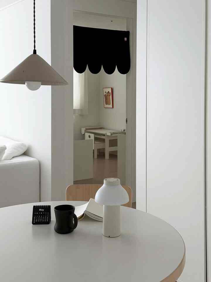 白とナチュラルな色調のシンプルなリビングと子供部屋があり、ホームカフェの要素を備えた落ち着いた空間