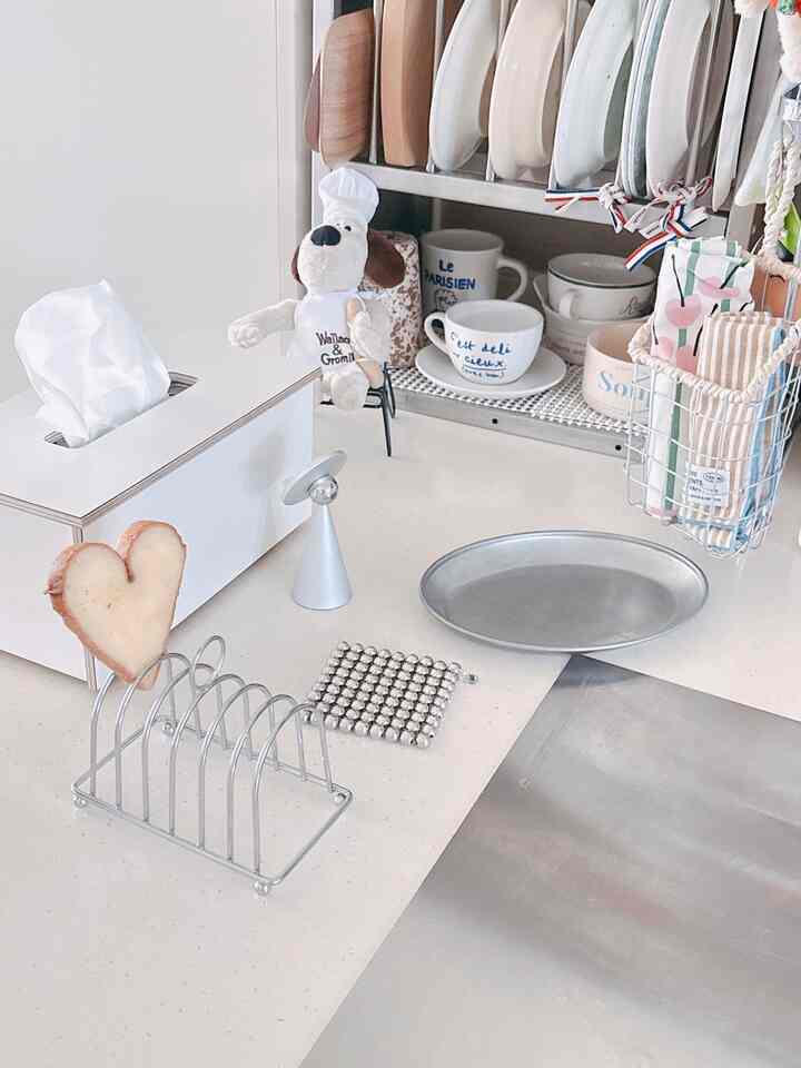 白を基調としたキッチン、整然と配された調理器具やまな板、コースターが印象的なモダンなインテリア