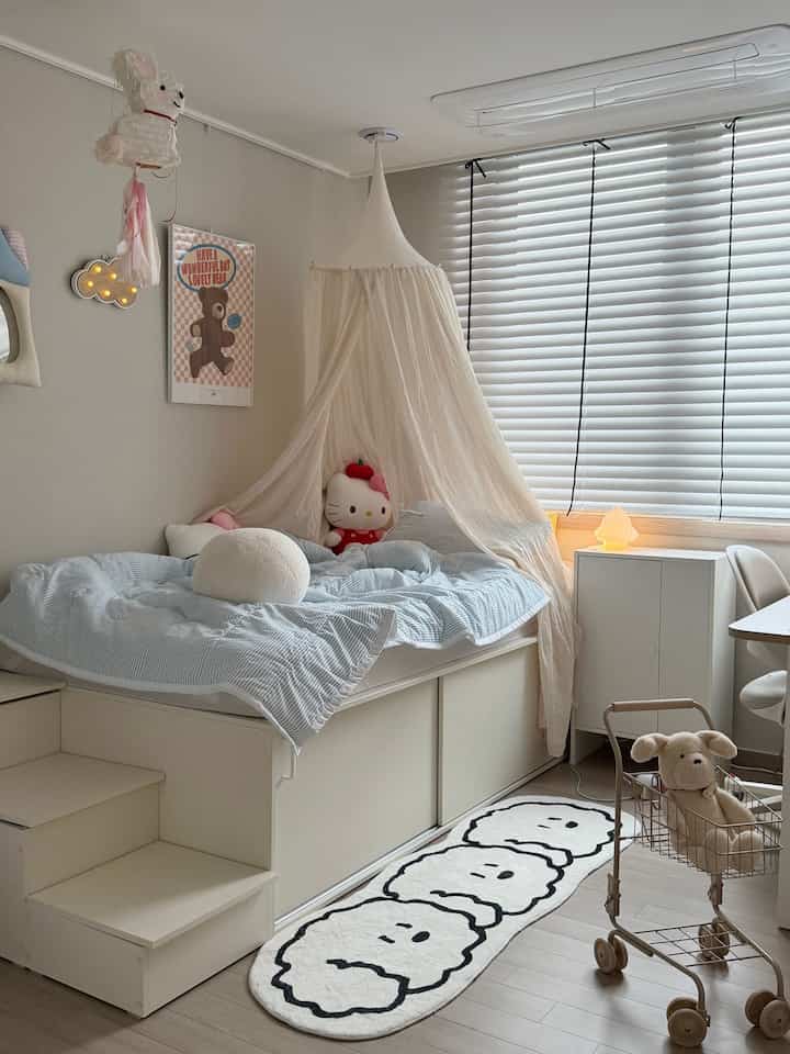 白とベージュの色調の子供部屋、ベッドキャノピーとかわいいおもちゃが配置された雰囲気のあるインテリア