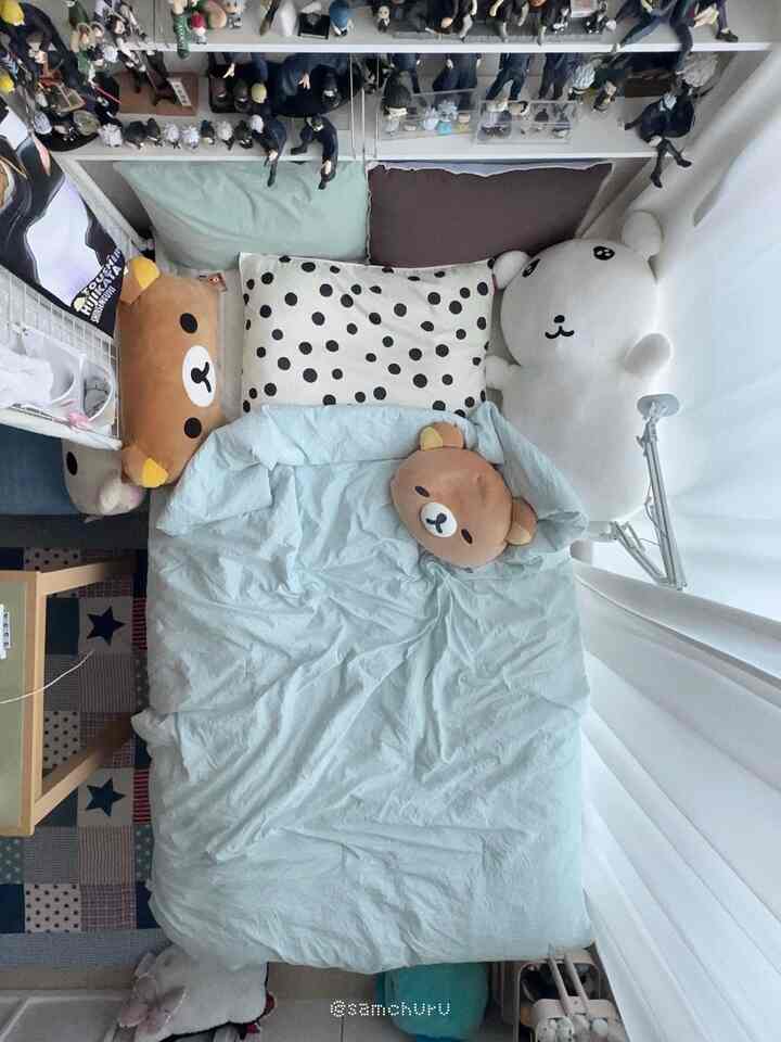 ミント色の寝具とかわいいクマのクッションが配置された、居心地の良い一人暮らしの寝室のインテリア