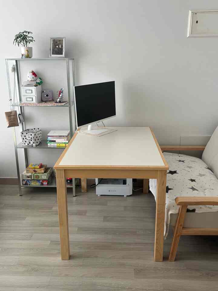 明るい白と木目調が調和したワンルームのホームオフィス、整頓されたデスクと金属製の棚が配置された落ち着いた雰囲気の空間