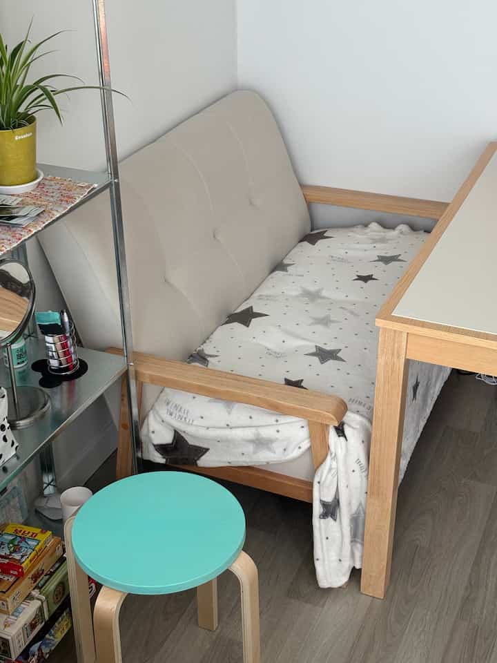 ホワイトと木目調が調和した狭いリビング、ベージュのソファとミント色のスツールが配置された雰囲気のある空間