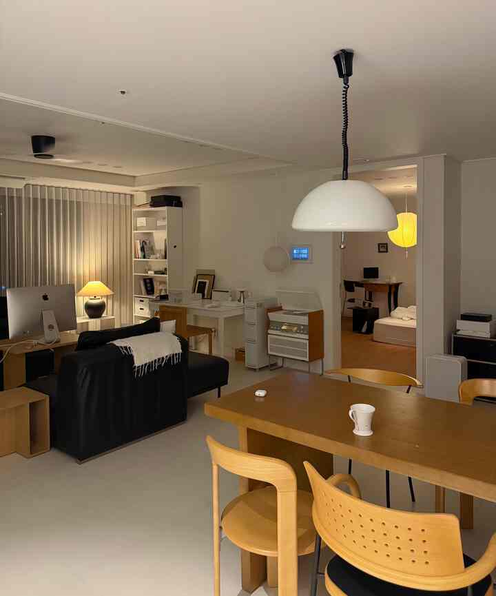 White and wood-toned living and dining room with a simple home office setup, creating a cozy atmosphere