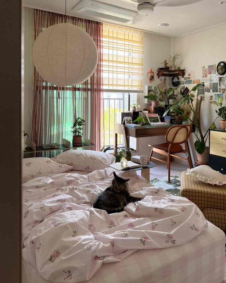 白とベージュ、木目調のワンルーム寝室、花柄寝具とペットの猫がいる自然なモダンなインテリア