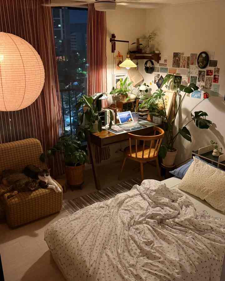 温かみのある木目調と植物が調和した寝室、デスクと二匹の猫がいる居心地の良いホームオフィス空間