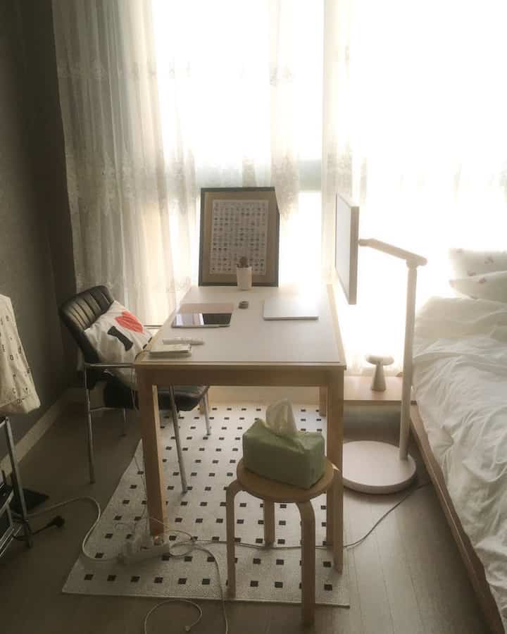 ホワイトとベージュのトーンで統一された6畳の部屋、デスクとアームチェア、ベッドが配置された雰囲気のあるホームオフィス