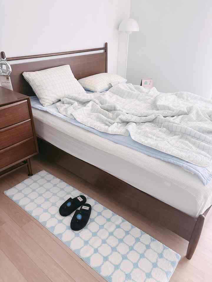 ホワイトと木目調が調和する寝室、シンプルで清潔感のあるベッドとドレッサーが配置された印象的な空間