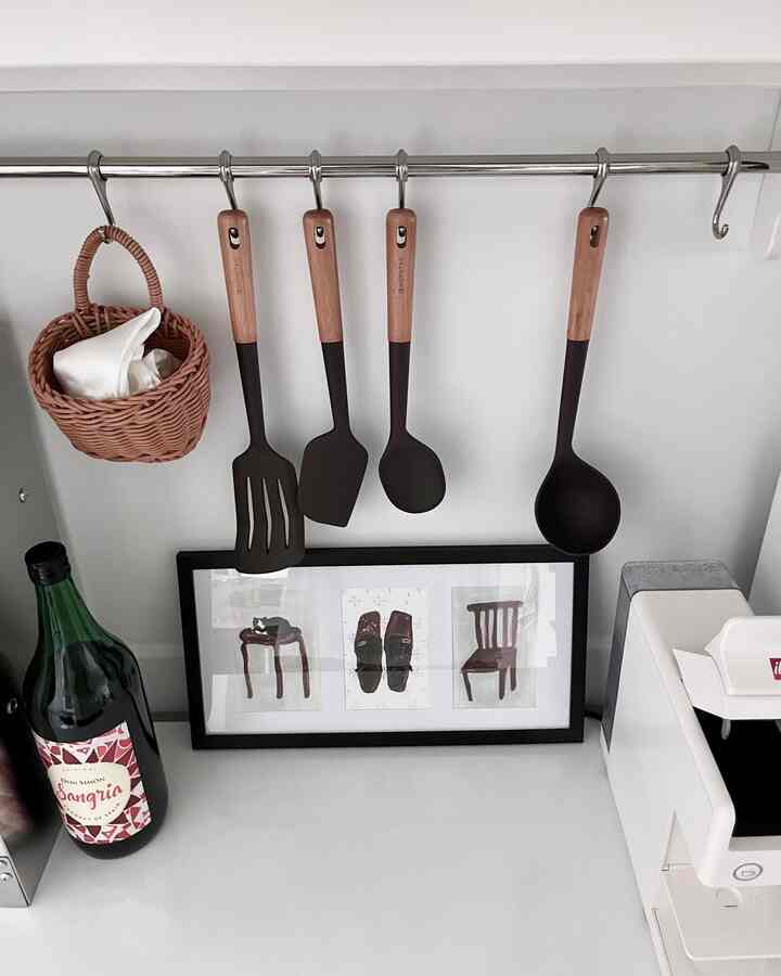 白い壁に調理器具とバスケットが掛けられた清潔なキッチンコーナー