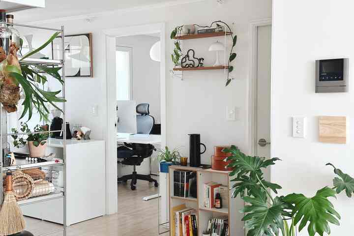 ホワイトと木目調が調和する小さなホームオフィス、植物と壁棚が落ち着いた雰囲気を演出しているインテリア