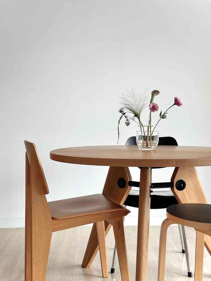 ナチュラルな木目調と白い壁が調和するダイニング、個性的な脚部を持つ丸テーブルと椅子が配置されたシンプルな空間