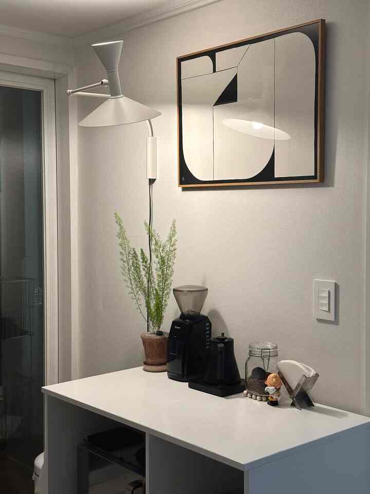 白と黒の調和が美しいモダンなキッチン空間、コーヒー器具と額縁が整然と配置されたおうちカフェの雰囲気のあるインテリア