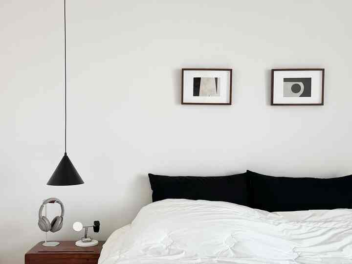 白と黒のトーンの寝室、シンプルなベッドとペンダントライトが配置されたモダンな空間