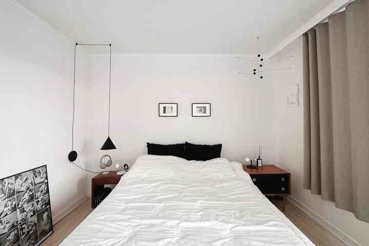 白と黒の調和が取れたシンプルな寝室、木製のロータイプベッドとナイトテーブルが配置された清潔な空間