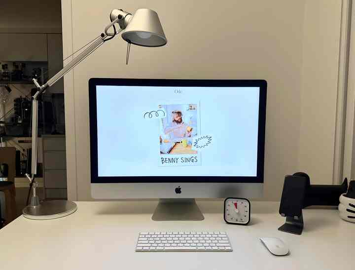 白とシルバーのモダンなホームオフィスのデスク空間、照明とタイマーが配置された清潔感のある作業環境