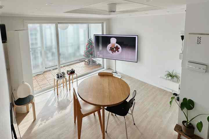 明るい白い壁と木目調の丸いダイニングテーブルが配置されたモダンで居心地の良いリビングとバルコニー空間