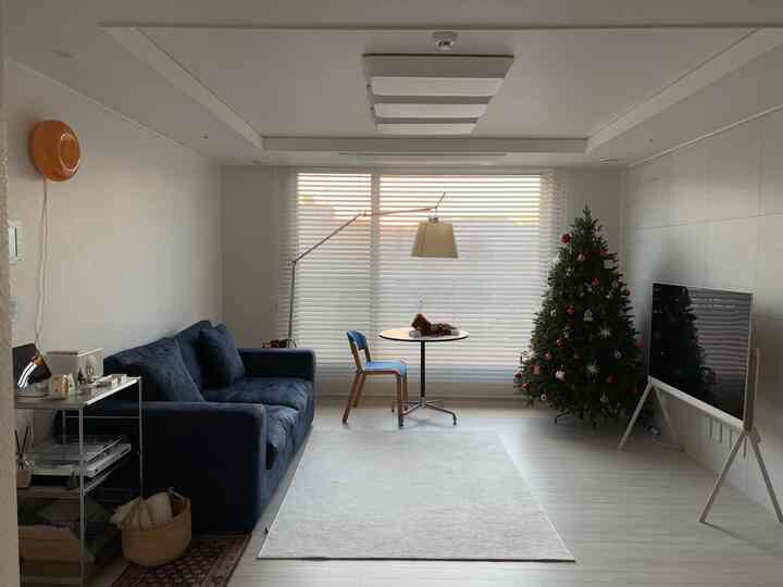 ホワイトとブルーのトーンのリビング、ソファとクリスマスツリーが配置されたシンプルで温かみのあるインテリア