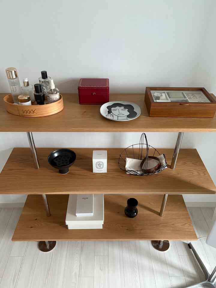 ナチュラルな木目調のヴィンテージ棚と様々な小物が配置されたシンプルで整ったインテリア