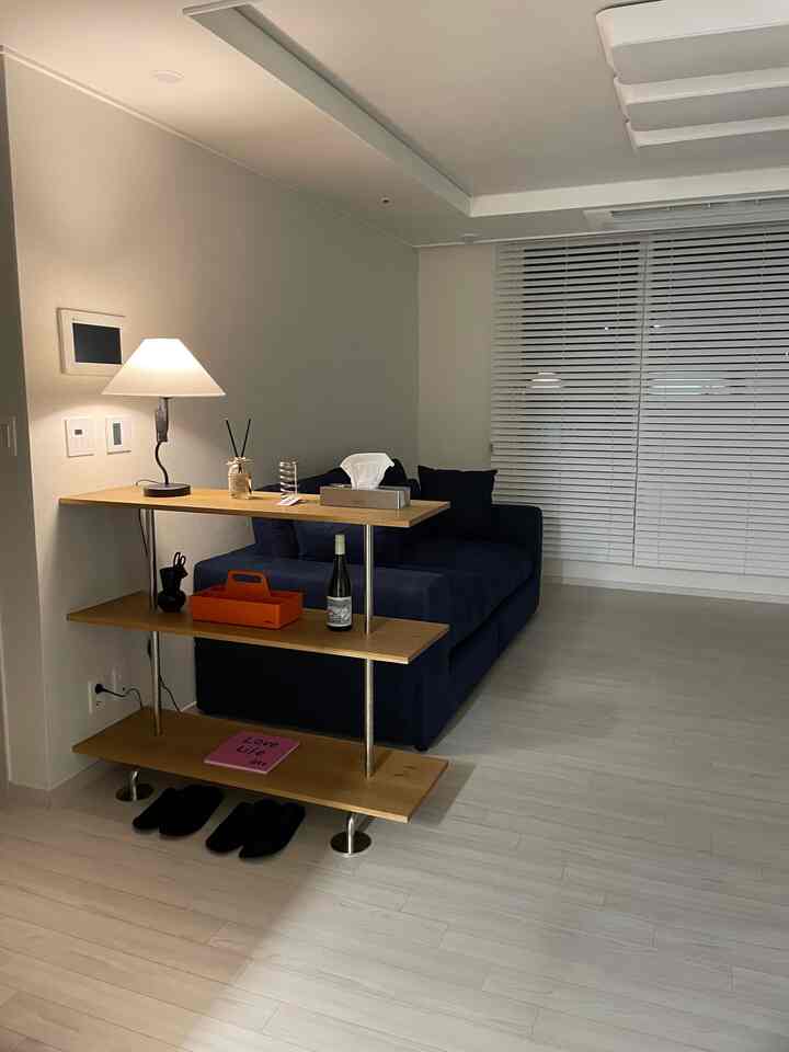 ホワイトとネイビーカラーのリビング、木目調の棚とソファが配置されたモダンな雰囲気のインテリア