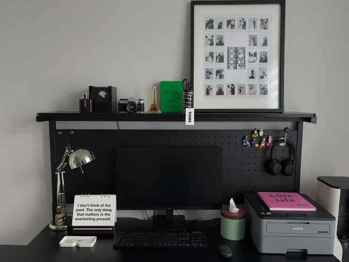 黒と緑のトーンのホームオフィス、モニターとデスクランプが配置された整ったワークスペース