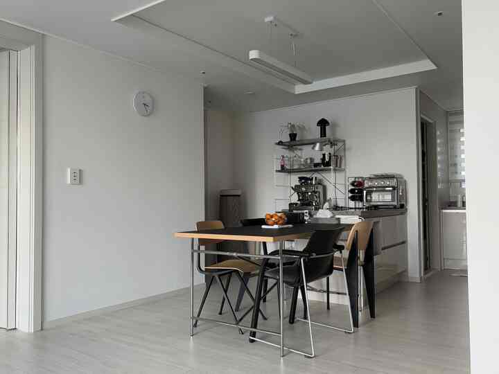 白と黒のモダンなダイニングルーム、中央にダイニングテーブルと椅子が配置され、コーヒーマシンがある清潔感のあるおうちカフェ空間