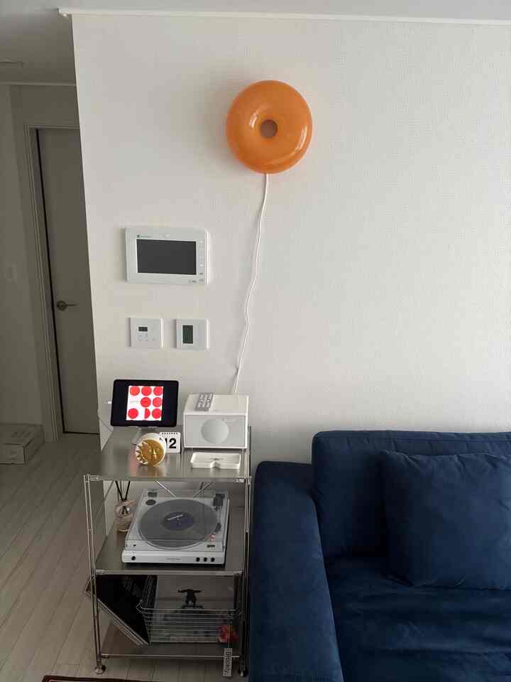 白い壁と床、ダークブルーのソファ、ステンレス製の棚、オーディオ機器が配置されたシンプルでモダンなリビングルーム