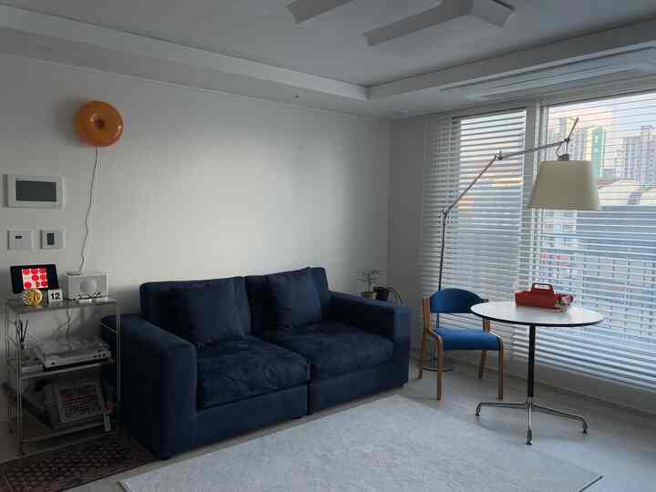 白を基調としたリビング、ネイビーのソファと小さな丸テーブルが配置されたモダンでコンパクトな空間