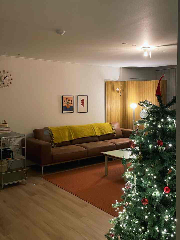 暖かいブラウンとオレンジ調のリビング、ゆったりとしたソファと季節感あるクリスマスツリー、木製の間仕切りが配置された雰囲気のあるインテリア