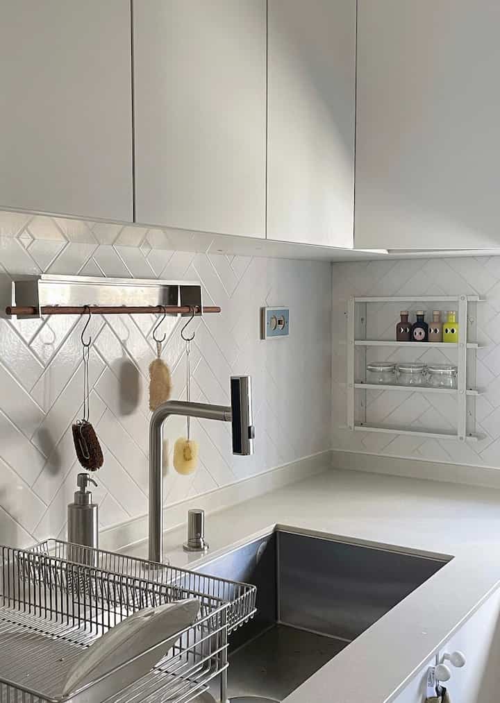 白色を基調としたモダンなキッチン、ステンレスの水栓や棚が配置された清潔感のある空間