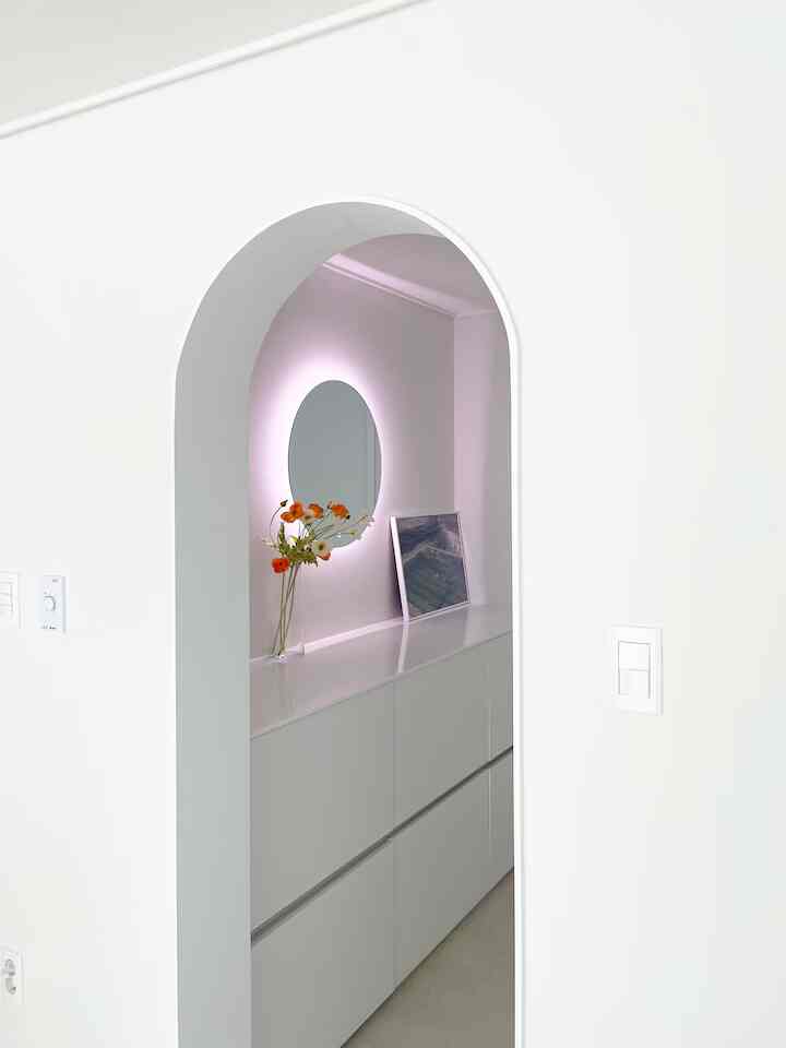 白を基調としたバスルーム、間接照明付きのタッチミラーと収納型の化粧台が配置された清潔感のある空間