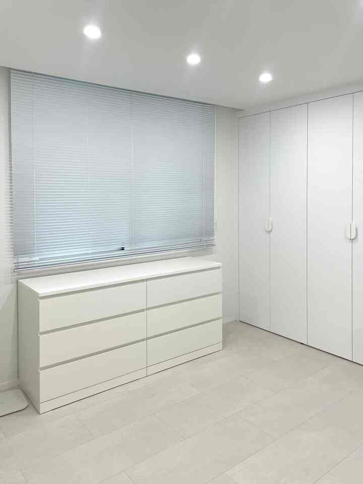 白を基調としたゲストルーム、シンプルで清潔感のあるチェストとビルトインクローゼットが配置された印象的な空間