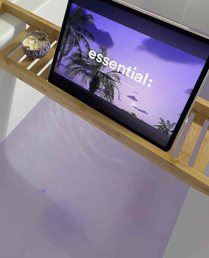 白い浴槽と木目調のバストレイ、ラベンダーカラーの背景が調和した落ち着いたバスルームのインテリア