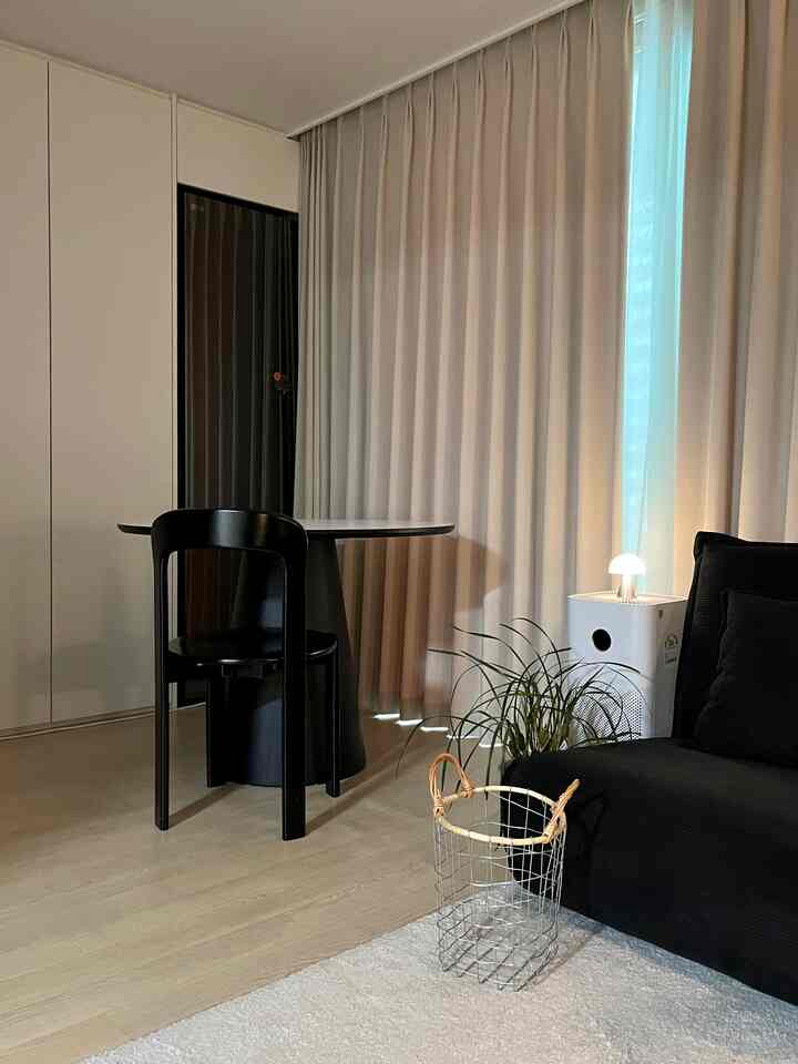 ベージュの遮光カーテンと黒い家具が配置されたモダンな二人用作業空間とリビングルーム