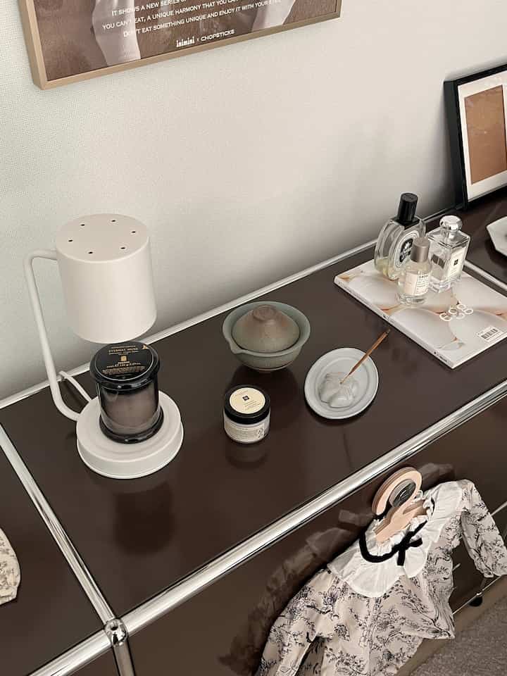 柔らかなブラウンとホワイトのトーンの玄関空間、USMキャビネットとベビー服、香水やインテリア小物が調和した温かみのある雰囲気のインテリア