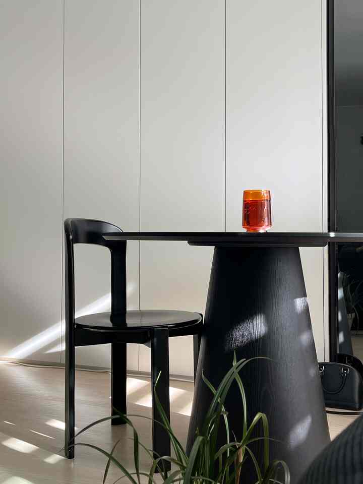 白い壁面と黒い丸テーブル・椅子が配置されたミニマルなインテリア空間