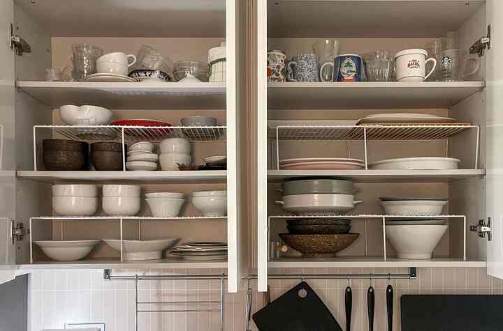 白を基調としたキッチンキャビネットに、多様な食器と食器ラックが整然と配置されたモダンなインテリア