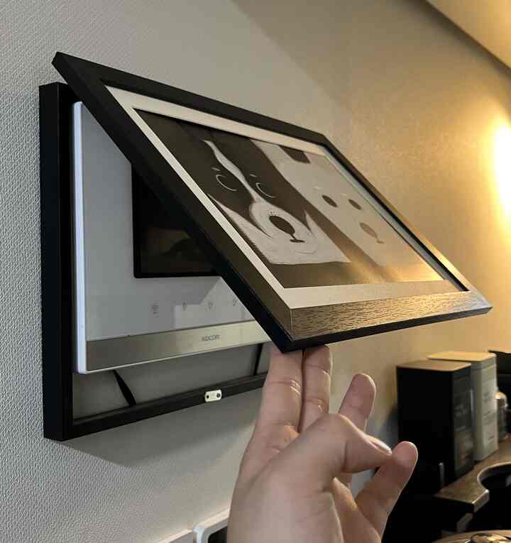 白い壁に取り付けられたインターフォンをマグネット式の額縁で覆った玄関の空間